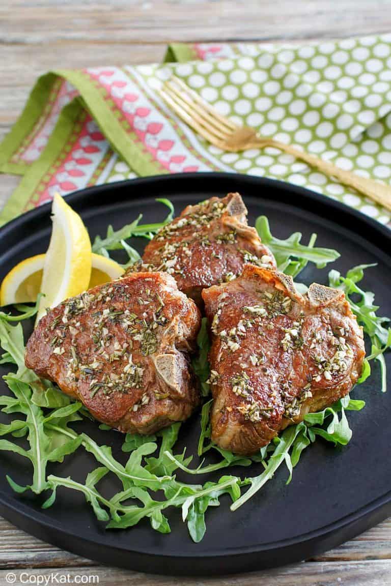 three pan seared lamb chops on a plate.