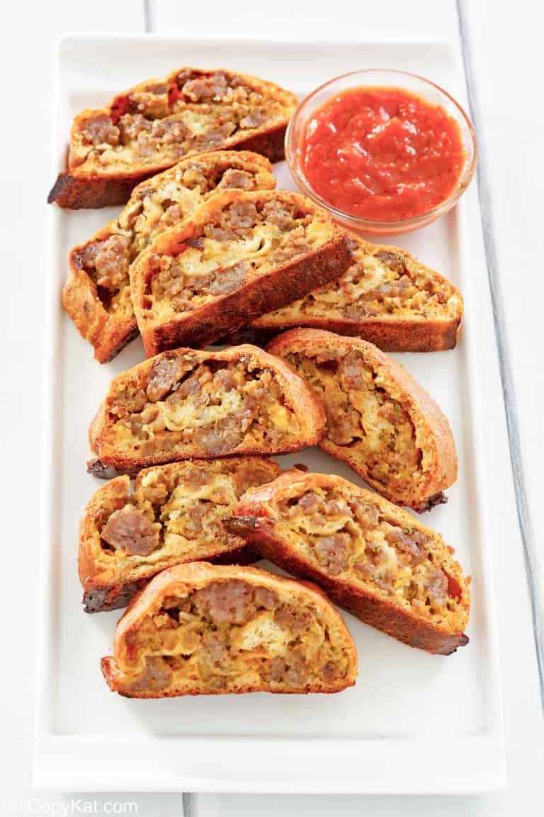 breakfast sausage roll slices and picante sauce on a platter.