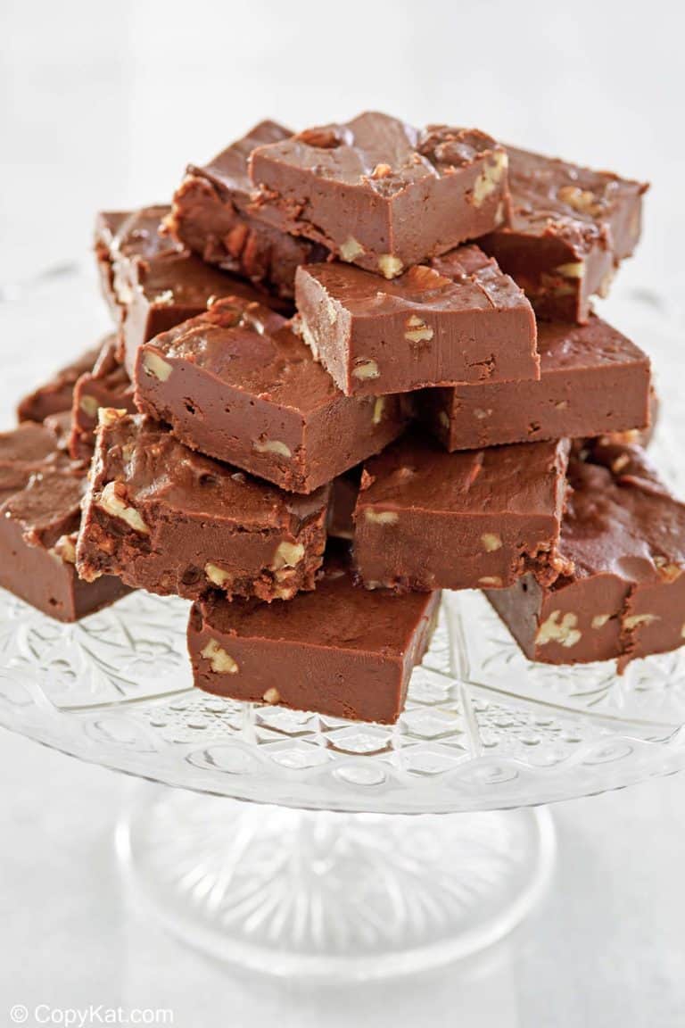 homemade See's chocolate fudge with nuts on a cake stand.