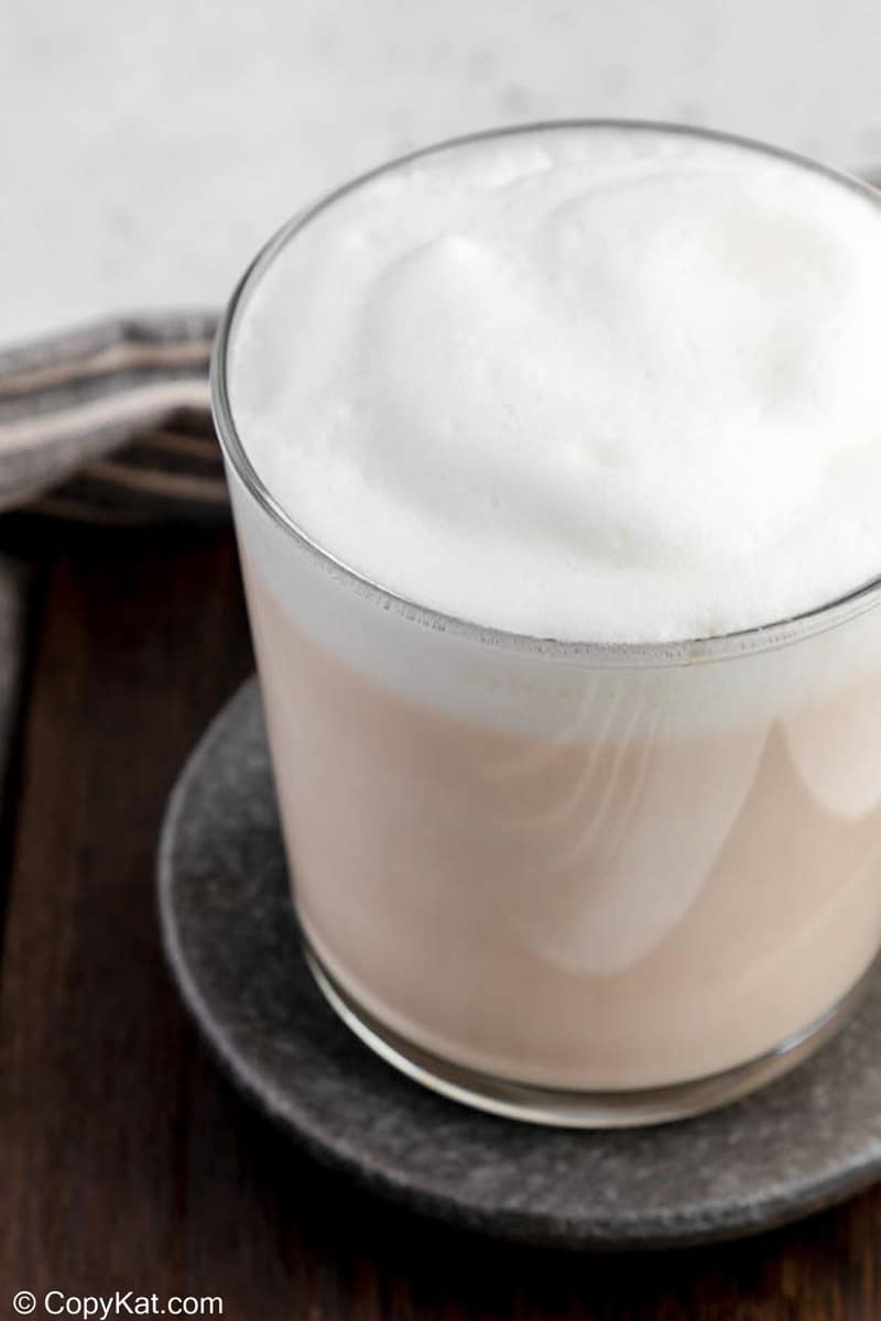 A detailed close-up of a London Fog latte, focusing on the thick, smooth, and airy texture of the white milk foam topping.