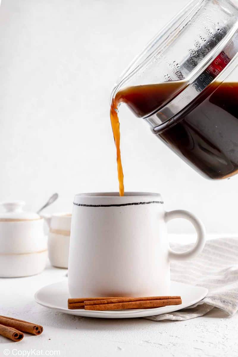 pouring cinnamon coffee into a mug.