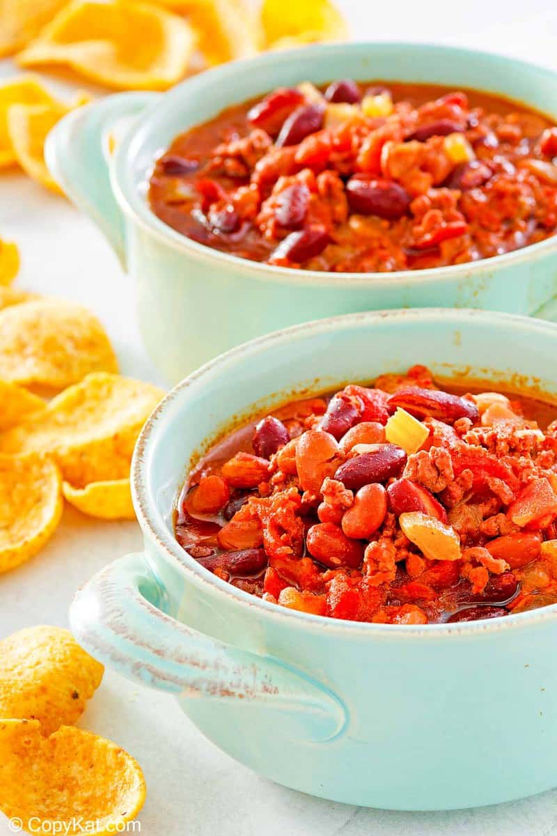 two bowls of crockpot chili and corn chips.
