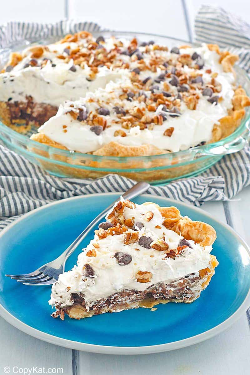 homemade Marie Callender's German Chocolate pie slice on a blue in front of the pie.