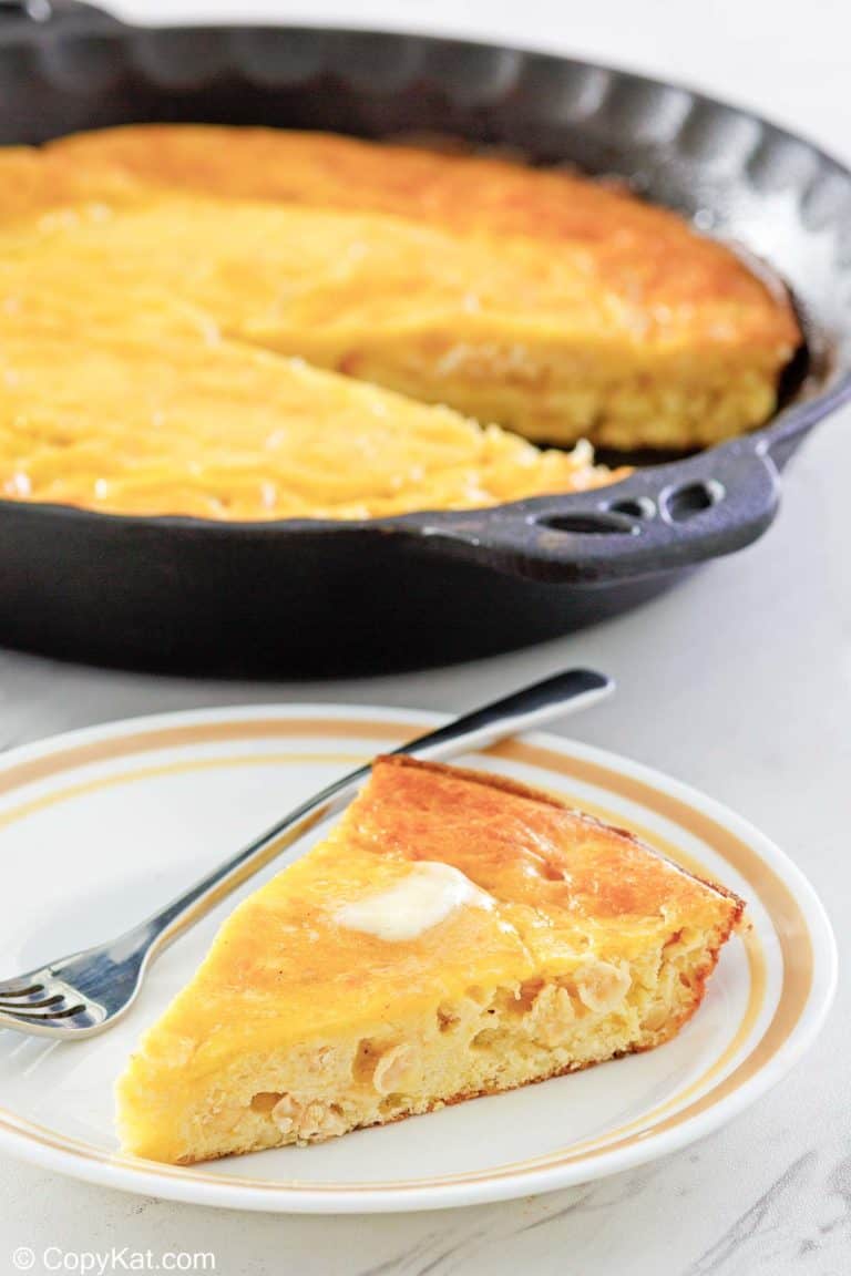 sour cream cornbread slice on a plate in front of cornbread in a skillet.