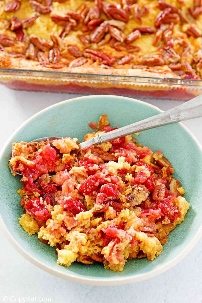 cherry pineapple dump cake in a baking dish and a serving in a bowl.