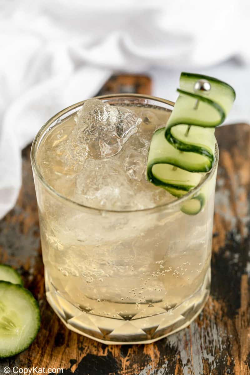 fleur de lis cucumber gin cocktail in a rock glass garnished with cucumber.