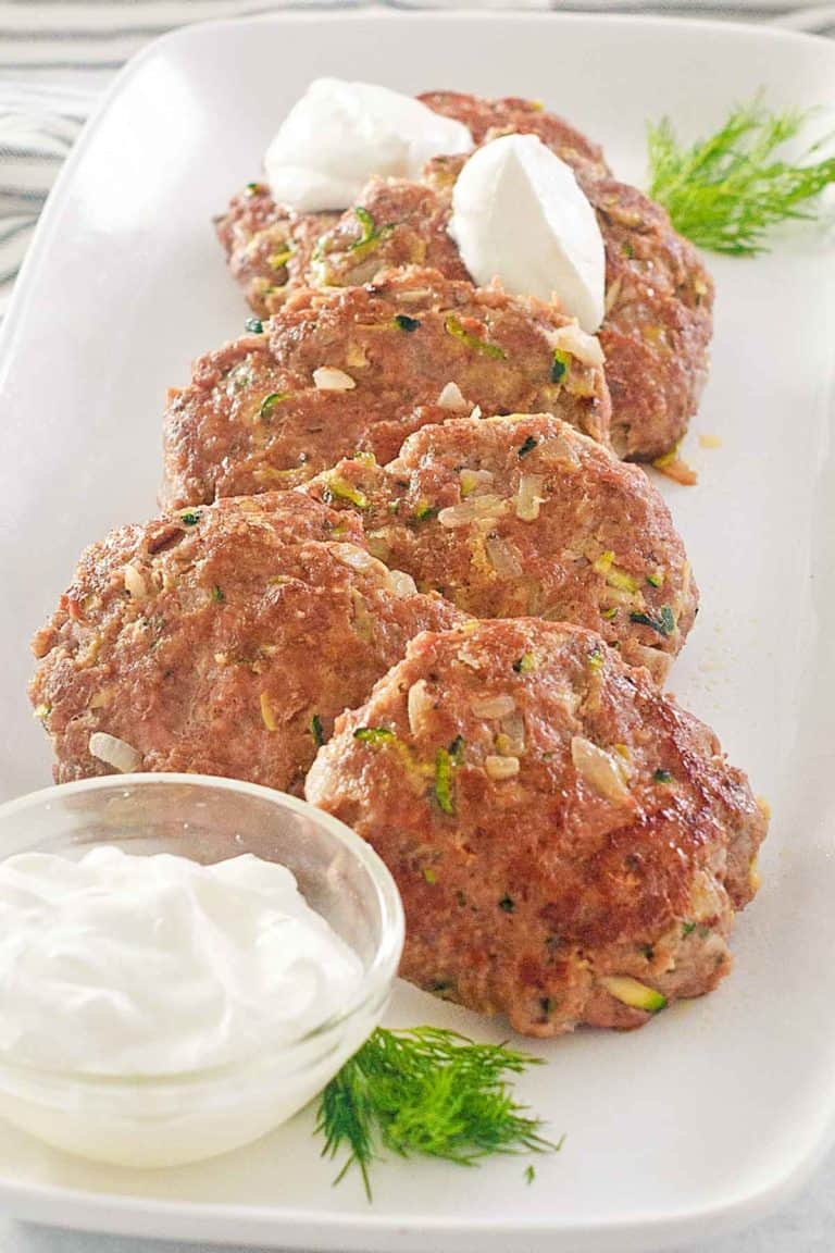 pan-fried chicken croquettes and sour cream on a platter.