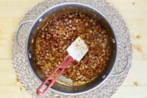 An overhead shot of a large pot where diced onions have been cooked with spices like chili powder and cumin, forming the aromatic base for the chicken enchilada soup.
