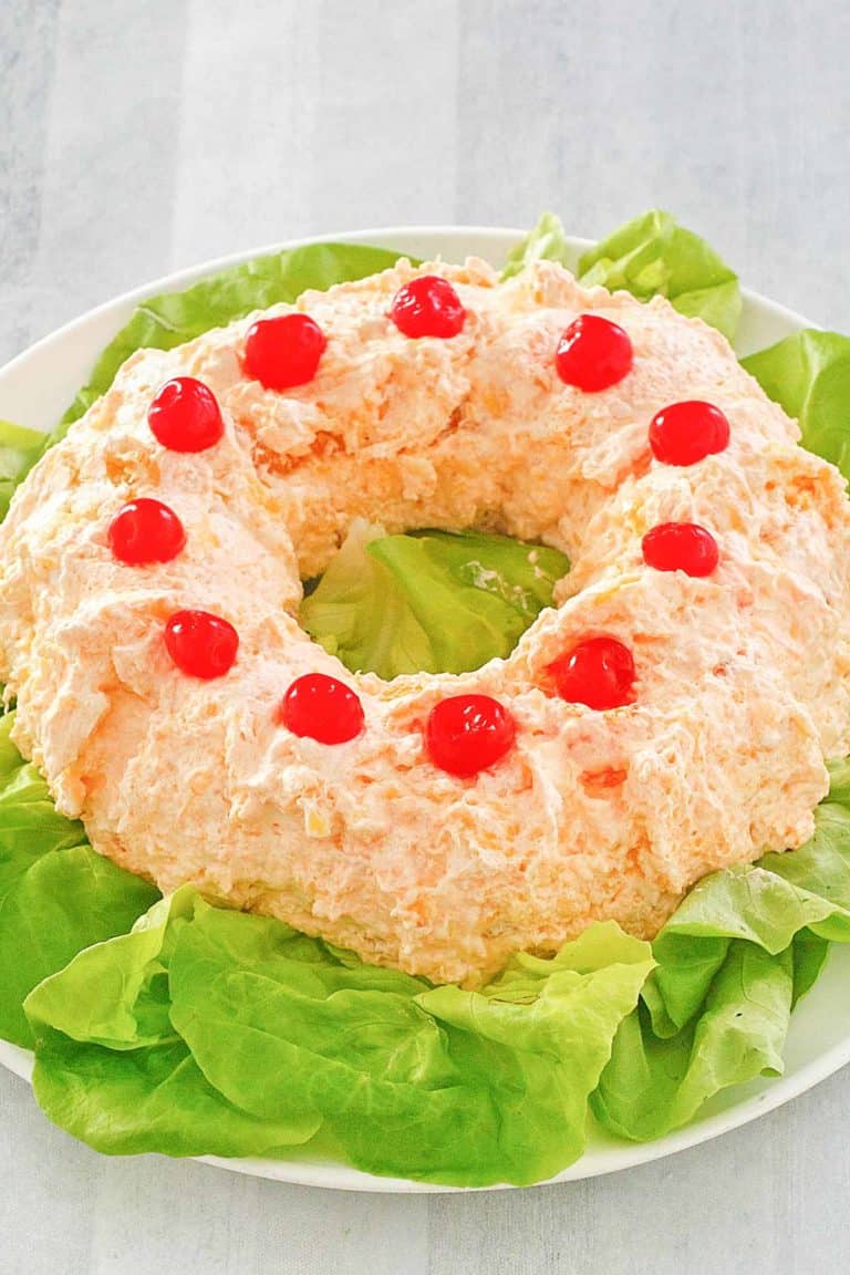 orange fluff jello salad on top of lettuce on a platter.