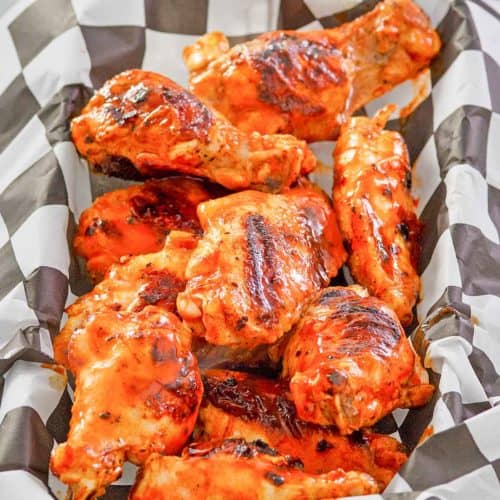 grilled buffalo chicken wings in a parchment paper lined basket.