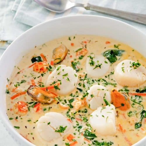 seafood bisque in a bowl and a spoon next to it.