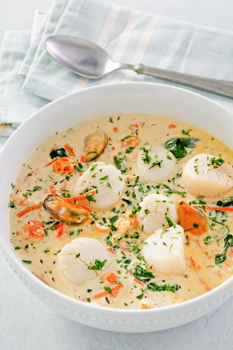 seafood bisque in a bowl and a spoon next to it.