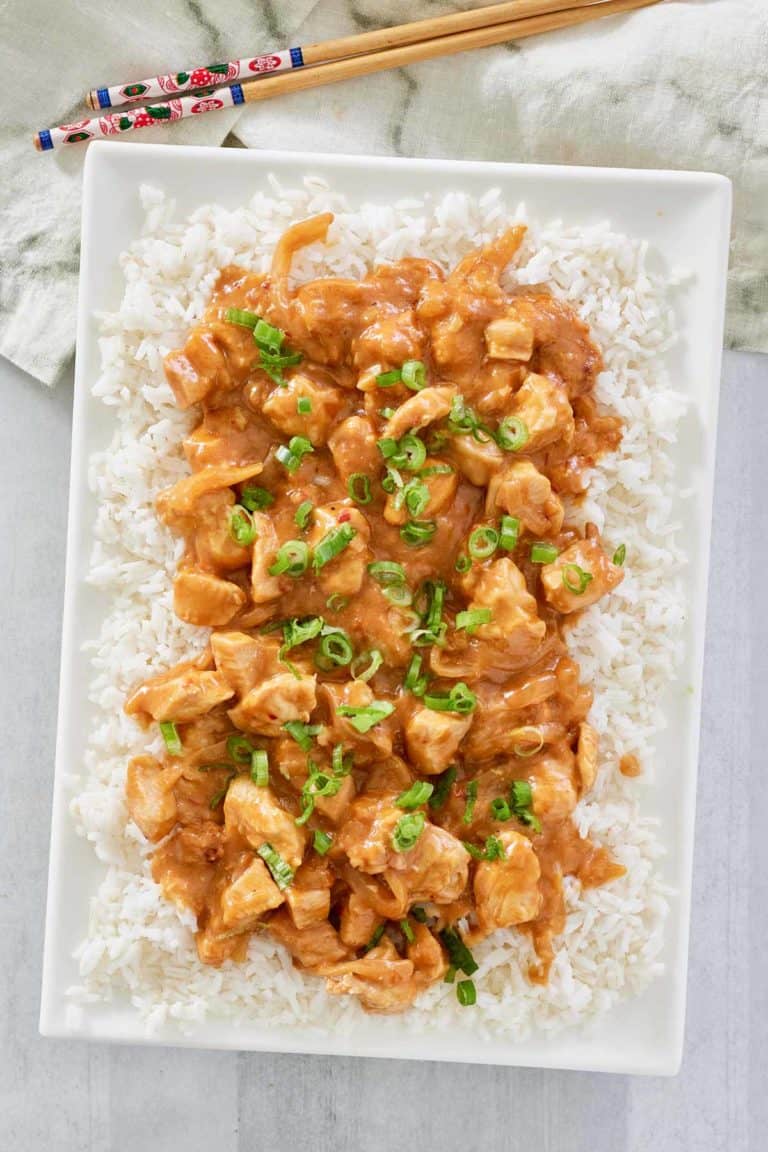 overhead view of Thai peanut chicken over rice on a platter.