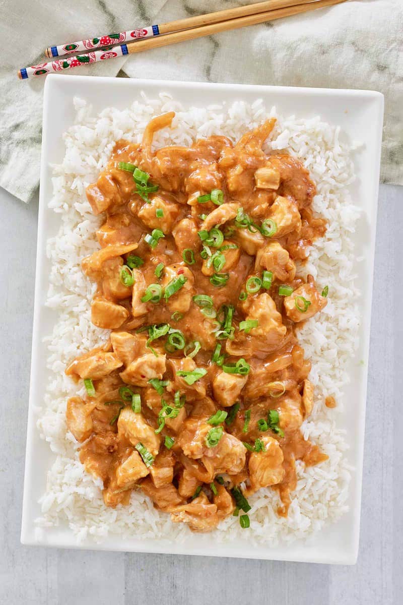 overhead view of Thai peanut chicken over rice on a platter.