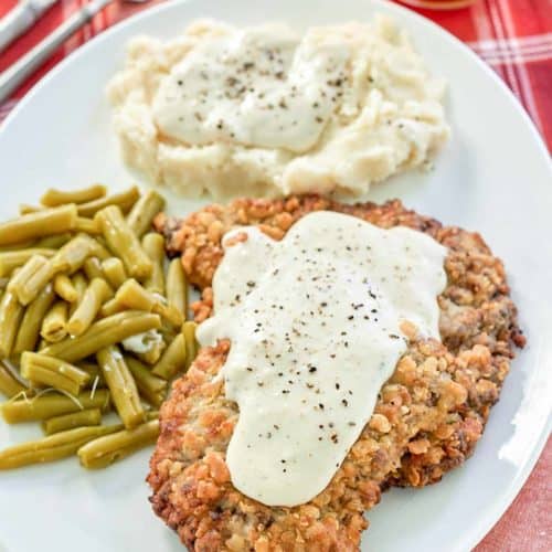 copycat Cracker Barrel country fried steak, gravy, and sides on a plate.