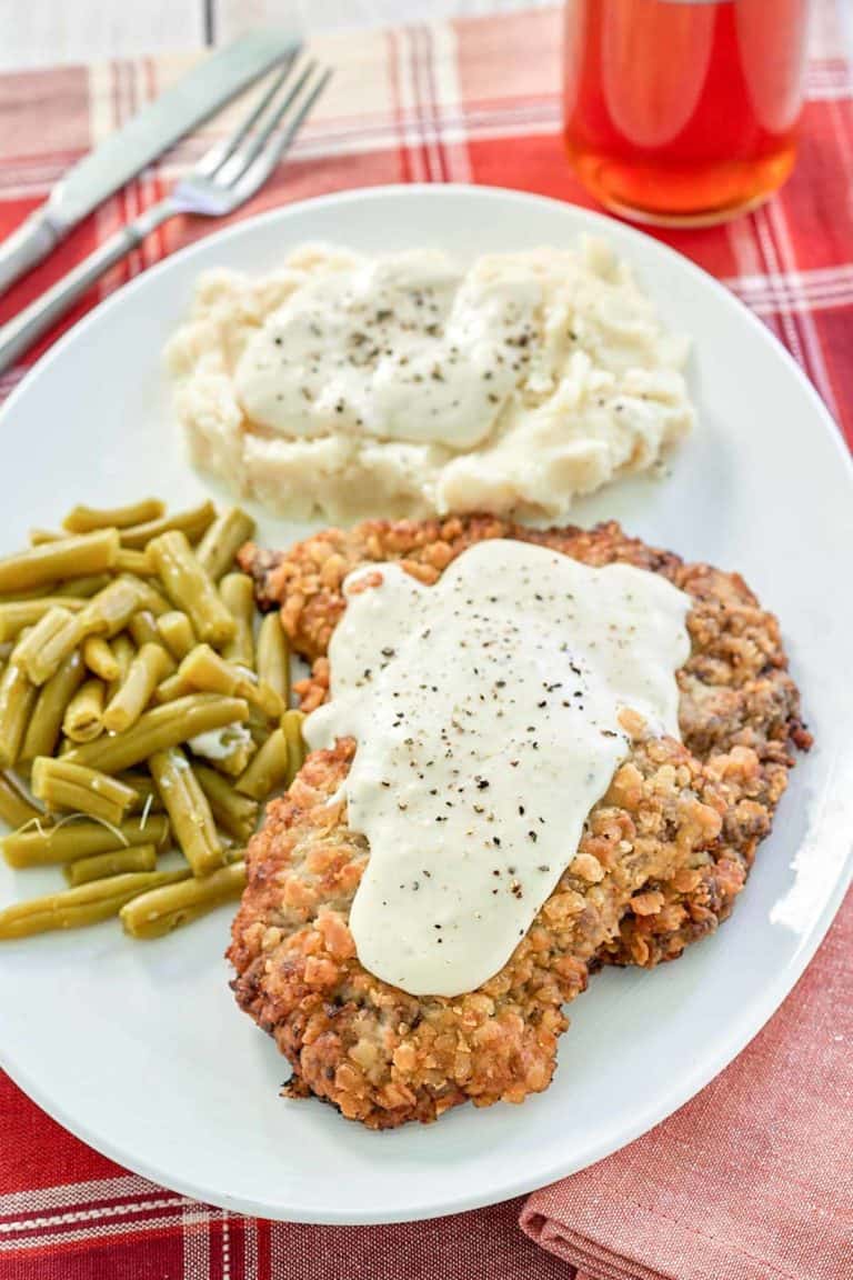 copycat Cracker Barrel country fried steak, gravy, and sides on a plate.