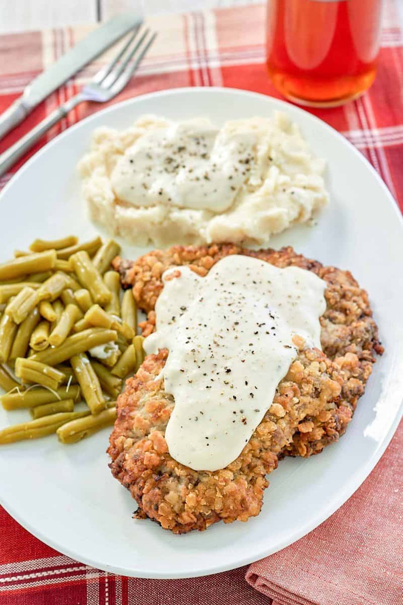 copycat Cracker Barrel country fried steak, gravy, and sides on a plate.