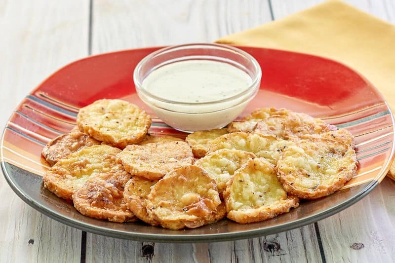A white plate piled with golden-brown, crispy mojo potato slices, sprinkled with seasoning, ready to be served.