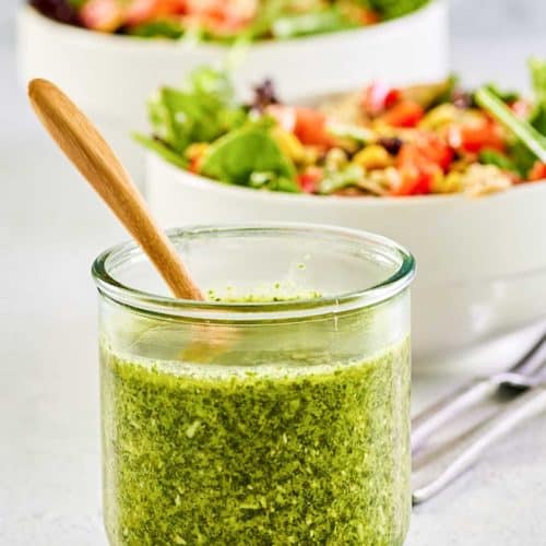 a jar of copycat Cheesecake Factory Santa Fe dressing in front of two salads.
