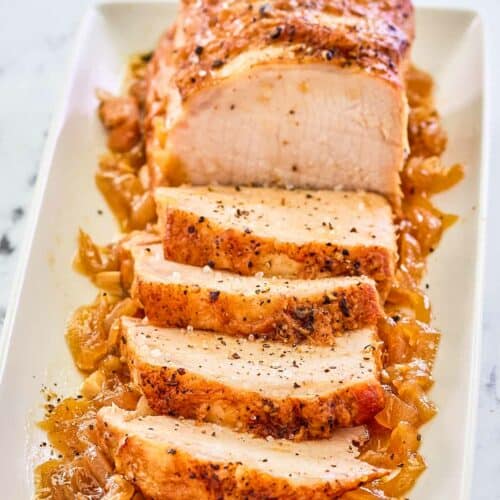 Instant Pot pork loin on top of cooked onions on a platter.