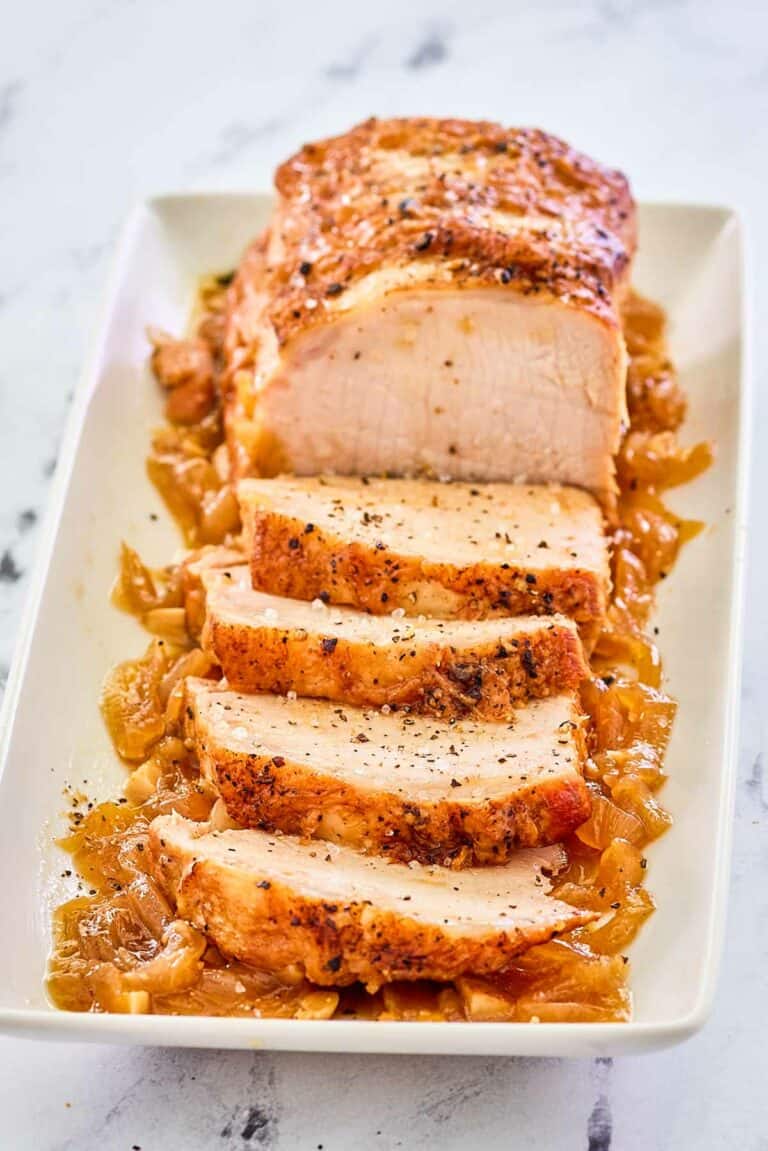 Instant Pot pork loin on top of cooked onions on a platter.