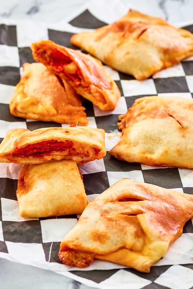 homemade pepperoni hot pockets scattered on parchment paper.