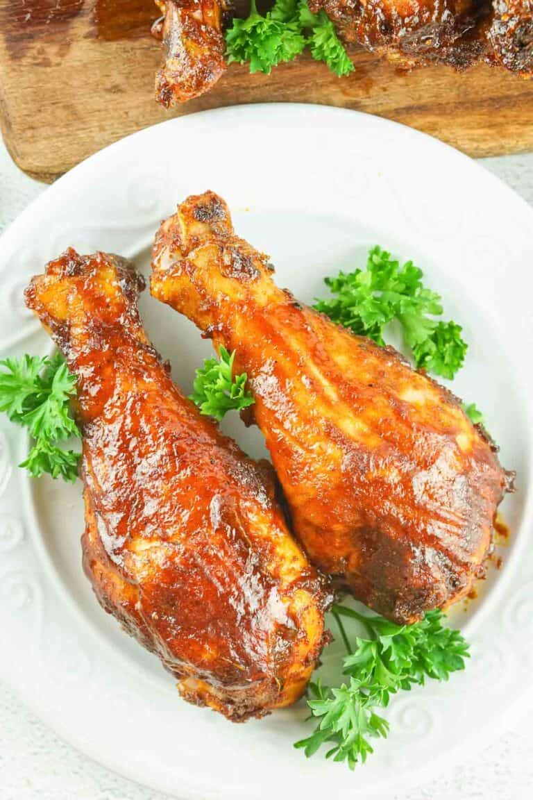 overhead view of two smoked chicken drumsticks on a plate.
