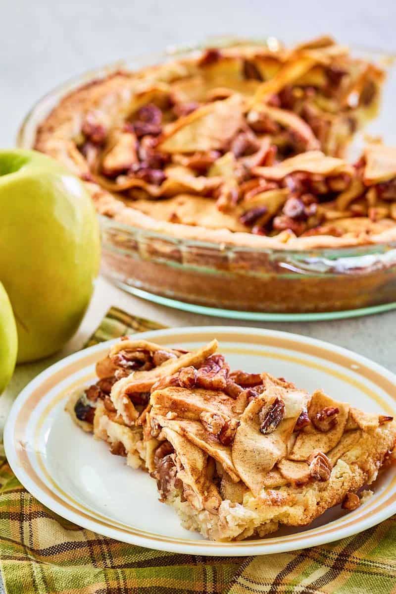 apple pie cheesecake slice on a plate in front of the dessert.