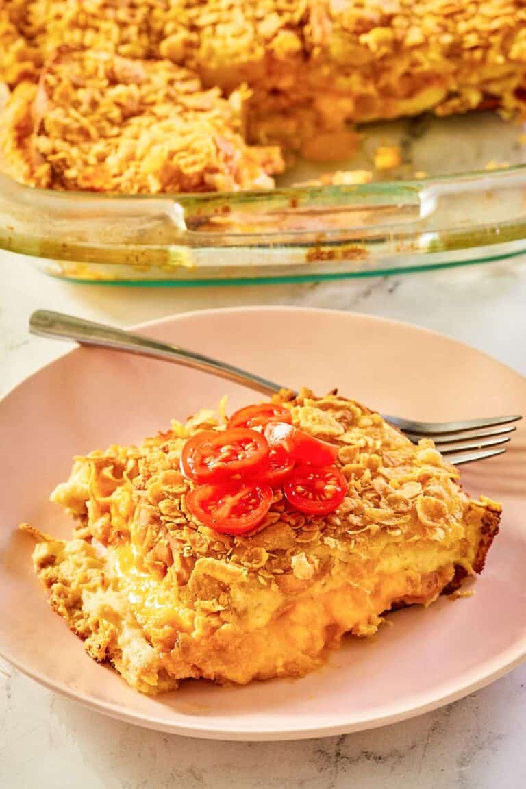 overnight breakfast strata serving on a plate in front of the strata.