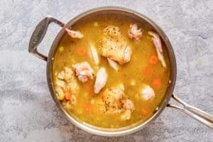 chicken thighs and vegetables cooking in chicken stock.