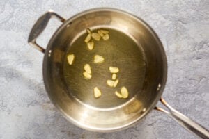 Olive oil and garlic slices in a pan.