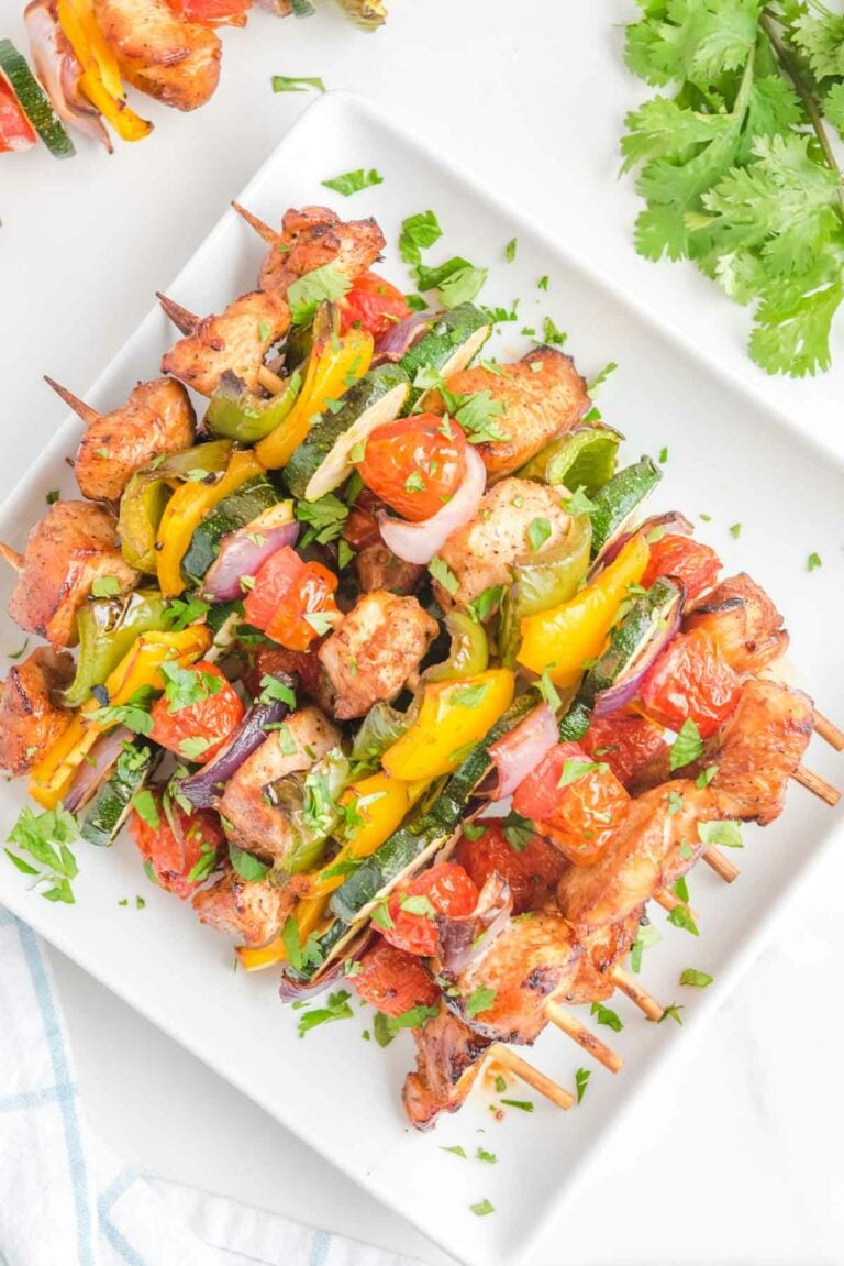 Overhead view of air fryer chicken kabobs on a square white platter.