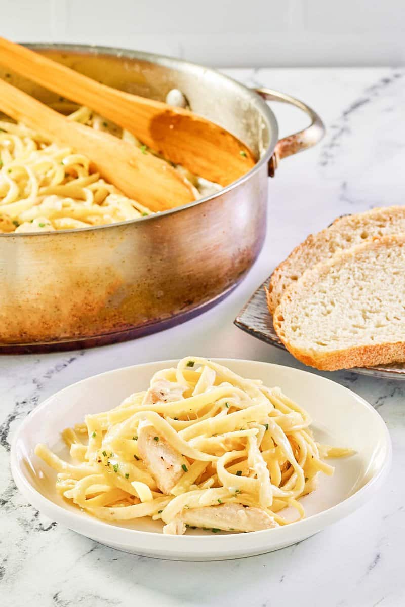 Chicken alfredo in a pot and a serving on a plate.
