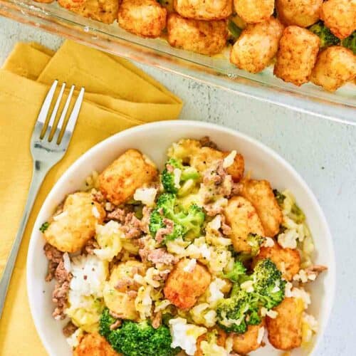 Overhead view of broccoli tater tot casserole with beef in a baking dish and a bowl.
