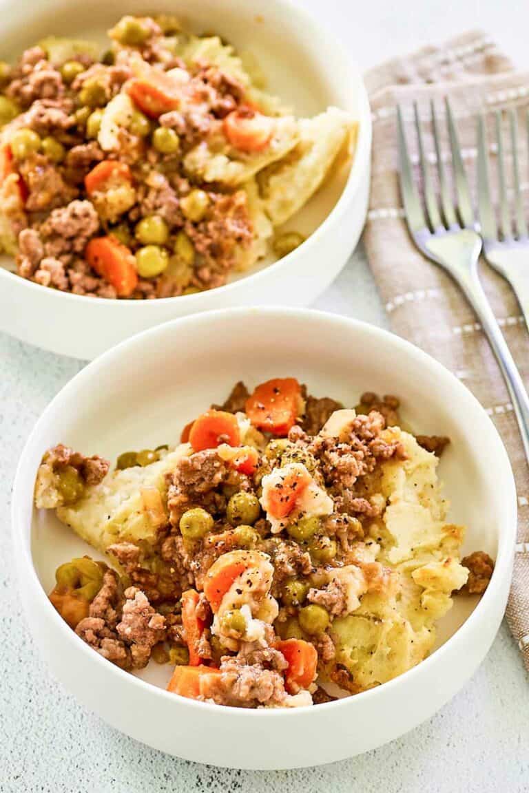 Two bowls of shepherd's pie with beef and two forks.