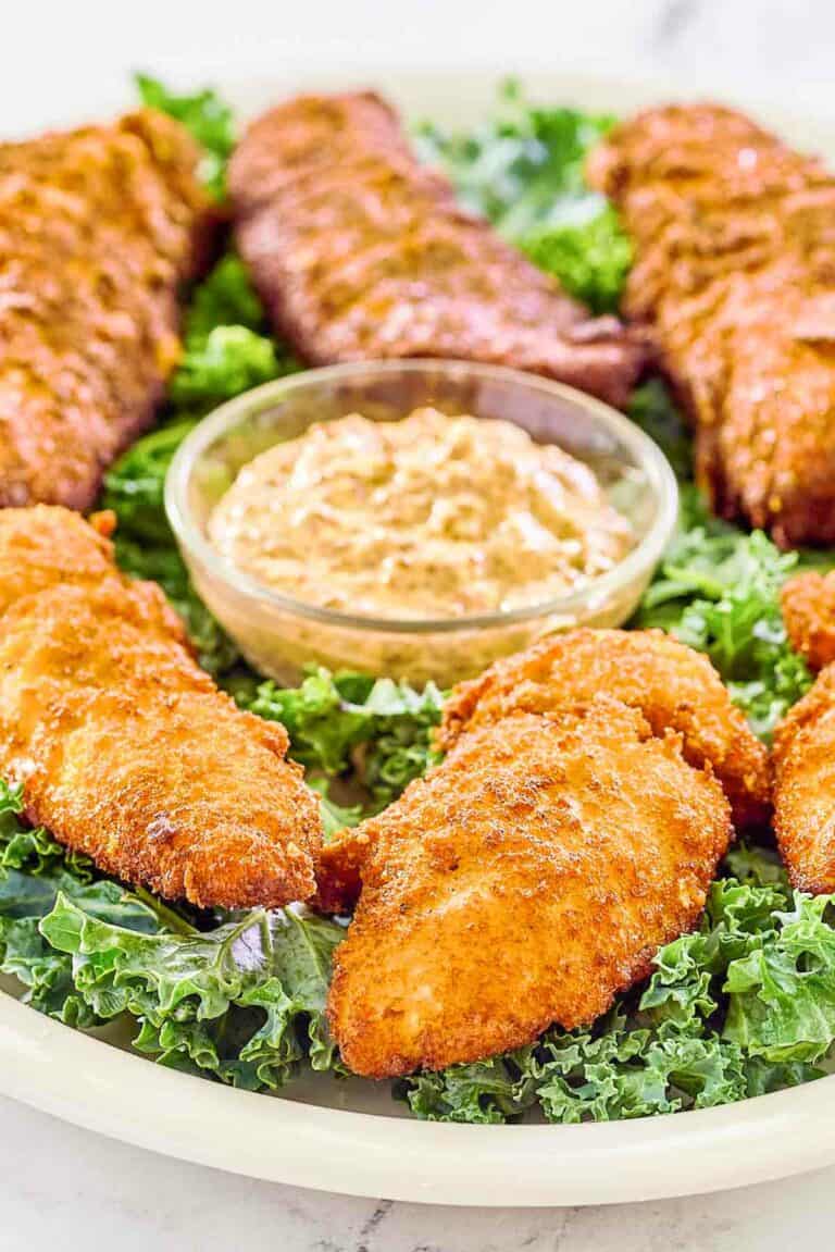 Copycat Captain Crunch chicken tenders on a platter with a bowl of Creole mustard.