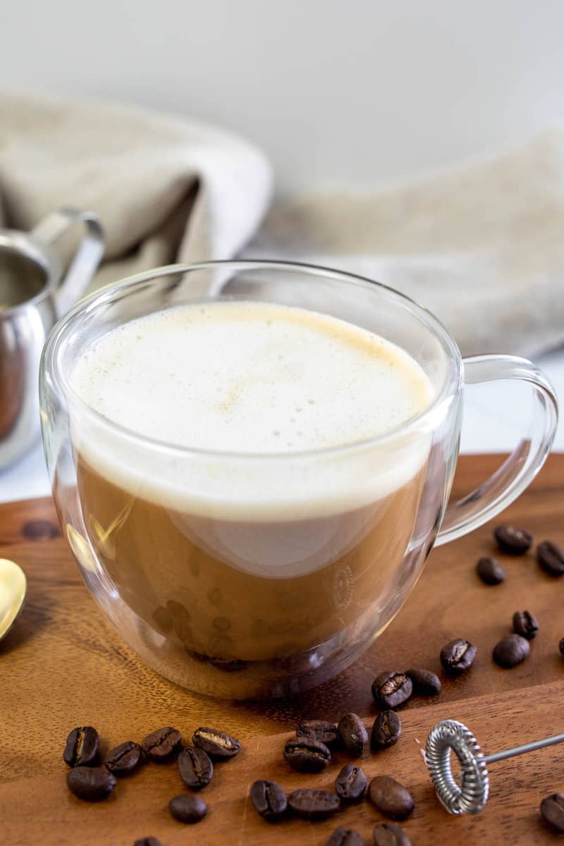 Copycat Starbucks Oleato caffe latte and coffee beans on a wood board.
