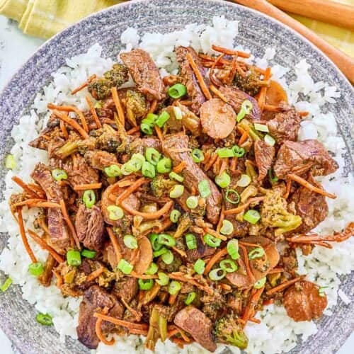 Overhead view of teriyaki beef stir fry over rice on a plate.
