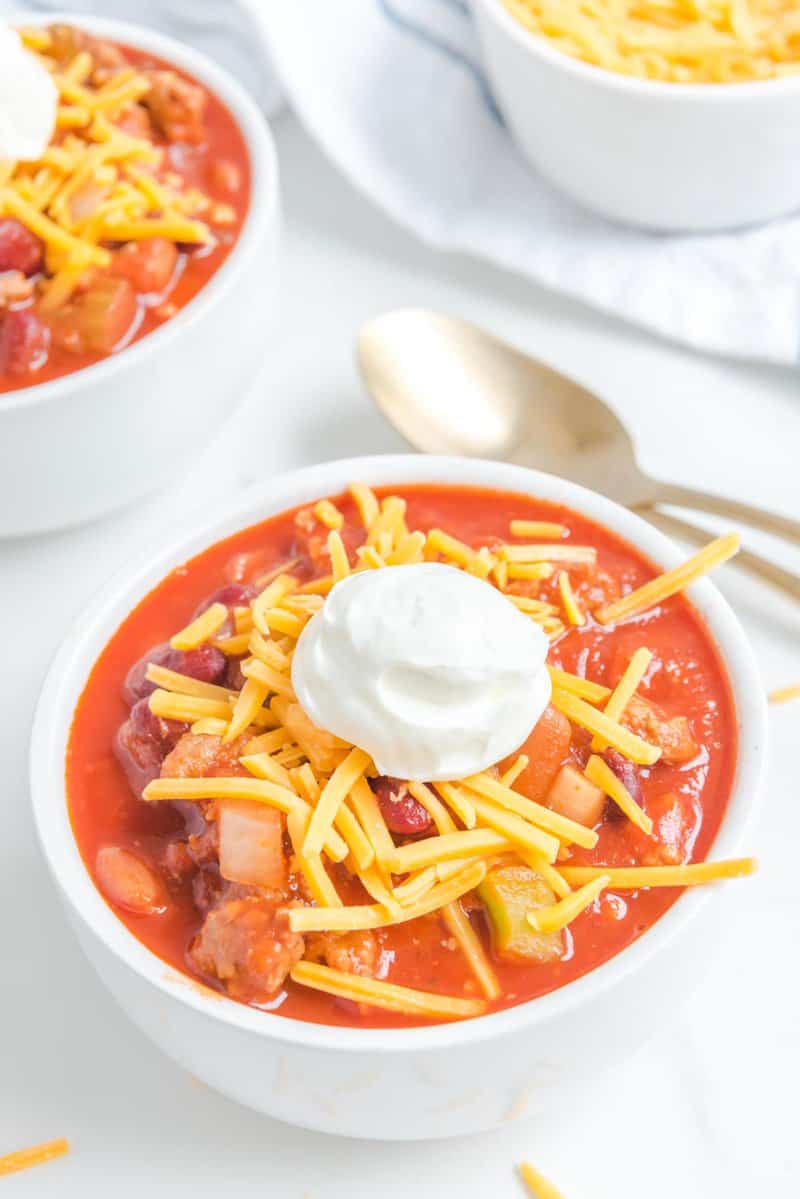 A close-up of a delicious bowl of Wendy's chili, served with classic toppings of shredded cheddar cheese and a dollop of sour cream.