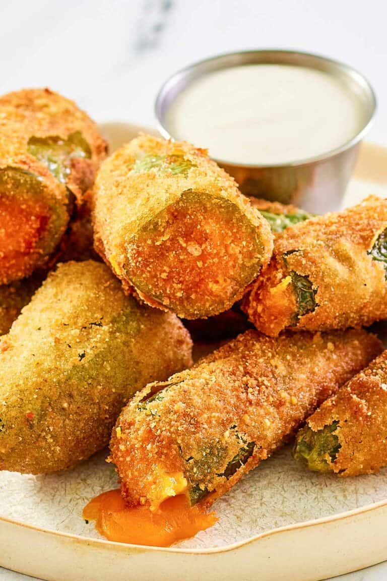 Cheddar cheese jalapeno poppers and a cup of dipping sauce on a plate.