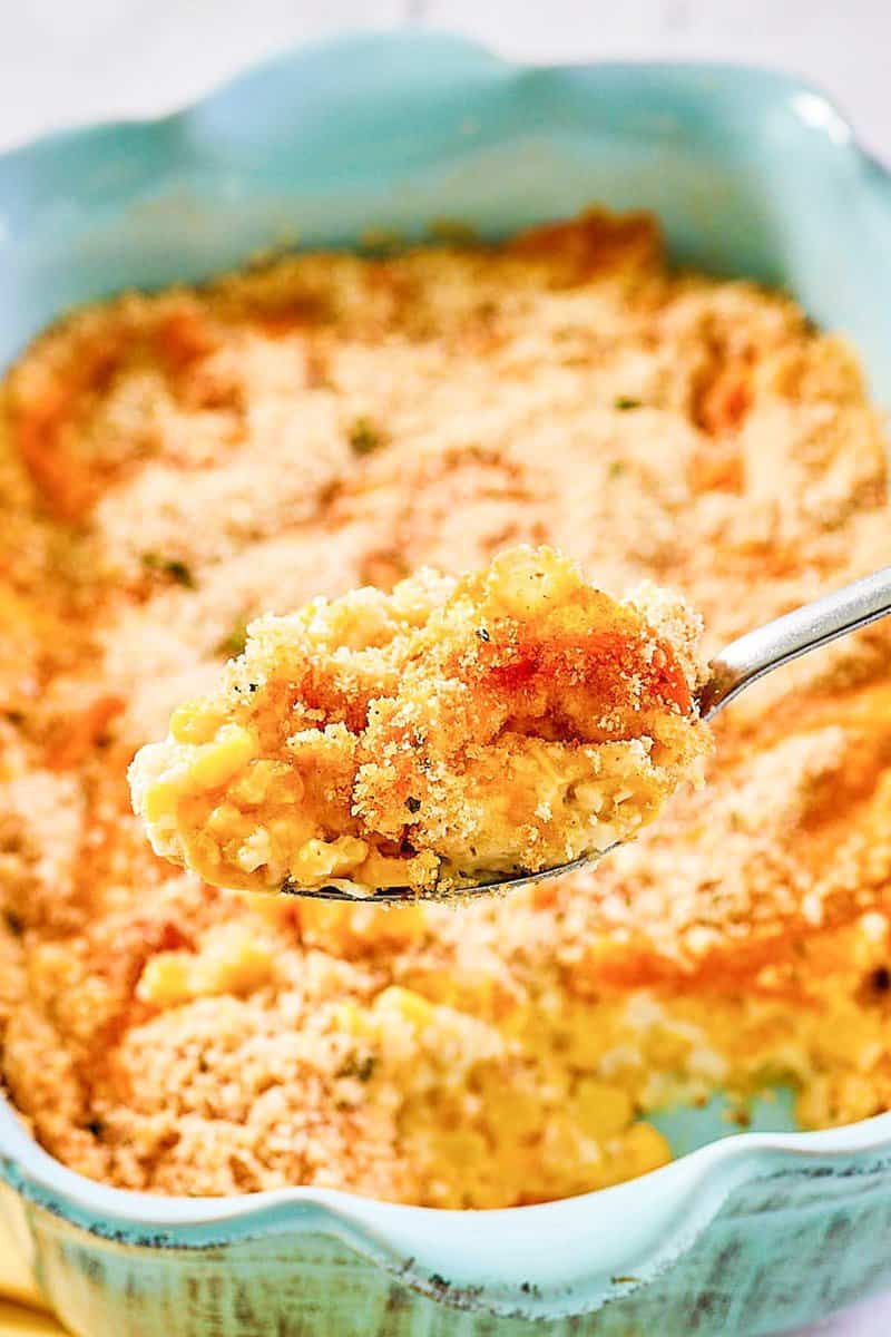 Creamed corn au gratin on a spoon and in a casserole dish.