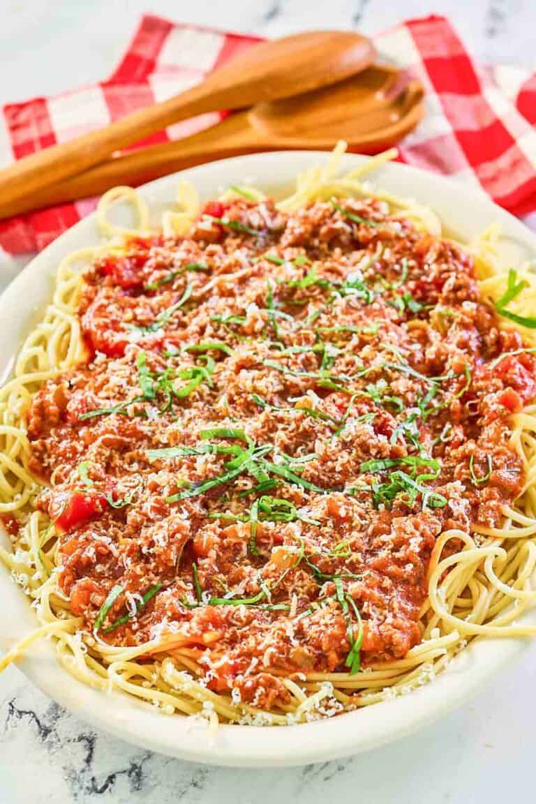 Homemade meat sauce over spaghetti on a platter.