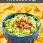 A bowl of sour cream avocado dip and tortilla chips around it.