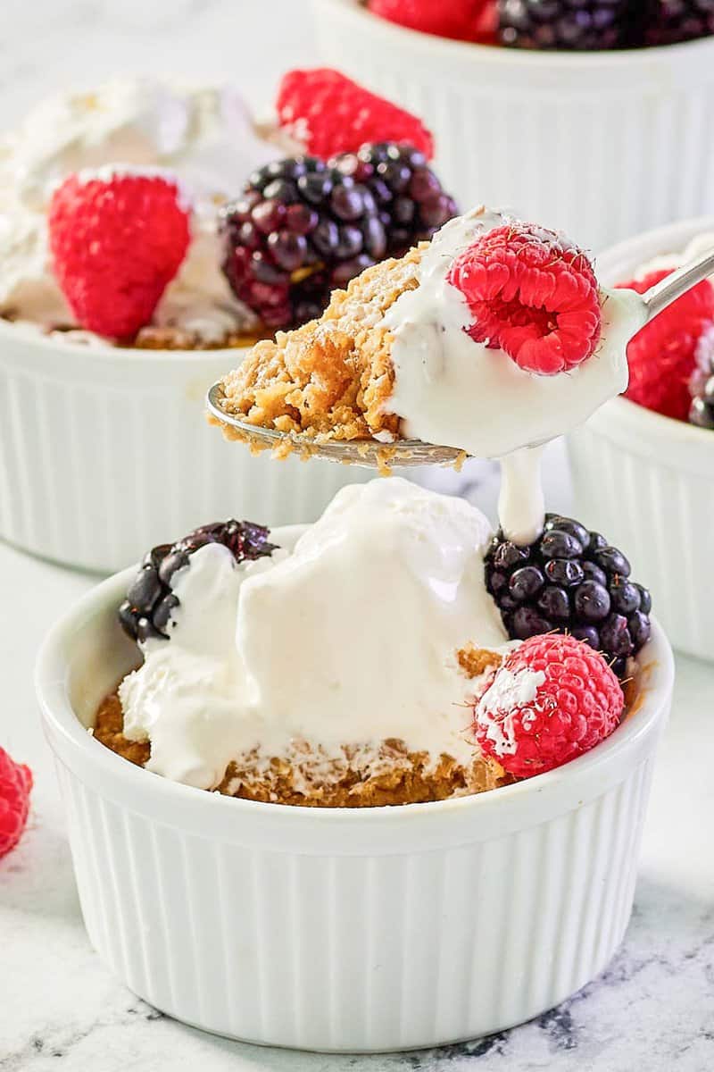 Copycat Brennan's oatmeal custard with whipped cream and berries on a spoon and in ramekins.