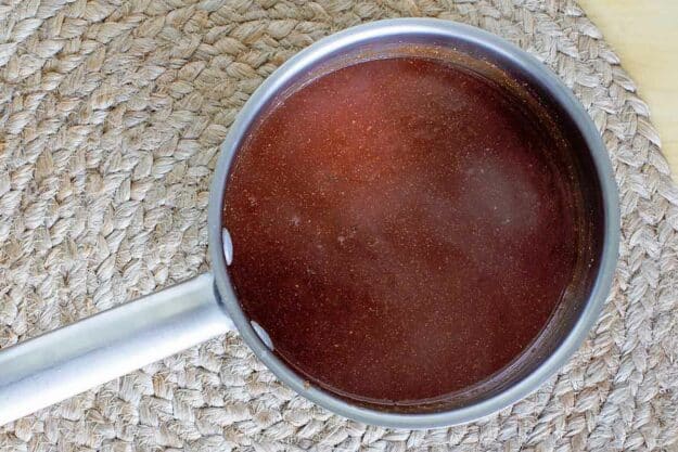 An overhead shot of a saucepan filled with dark red Arby's sauce, simmering and ready to be served.
