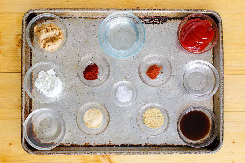 Ingredients for Arby's sauce arranged on a baking sheet: ketchup, spices, brown sugar, vinegar, and Worcestershire sauce.