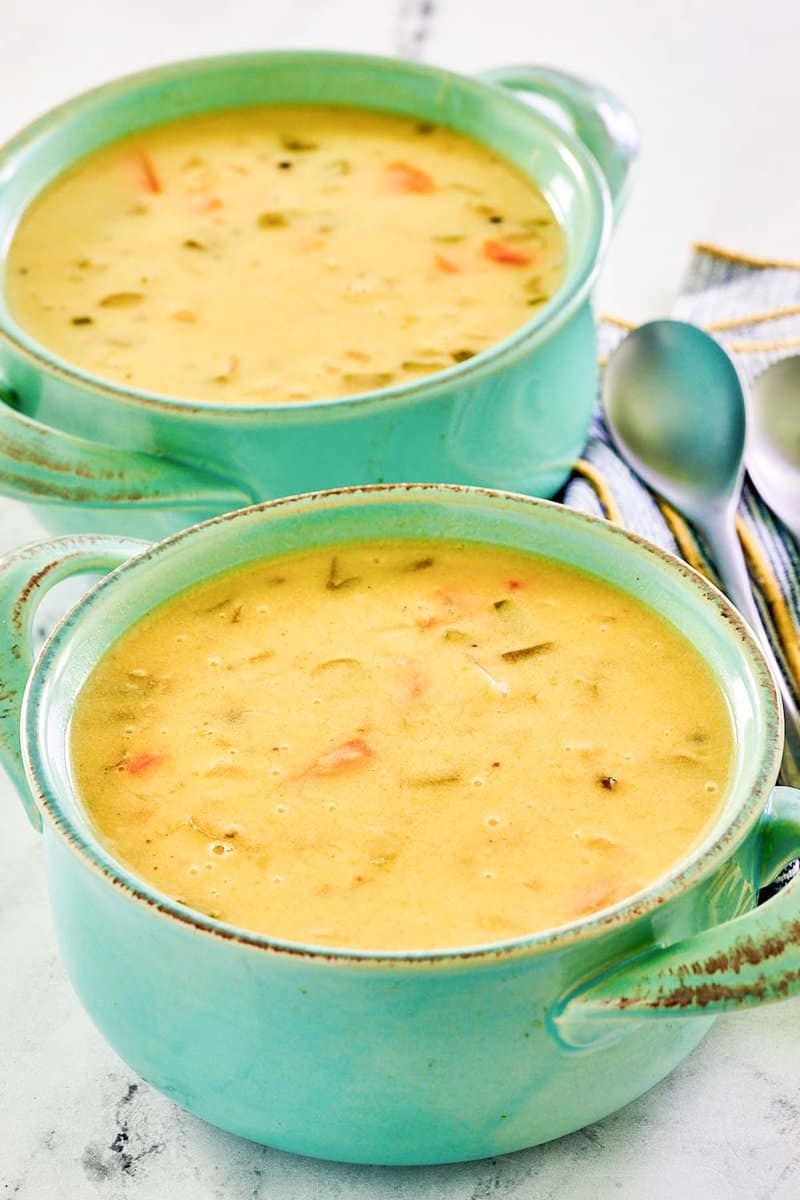 Homemade cheddar cheese soup in two soup crocks.