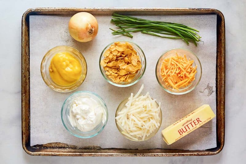 Hashbrown casserole with cornflakes ingredients on a tray.