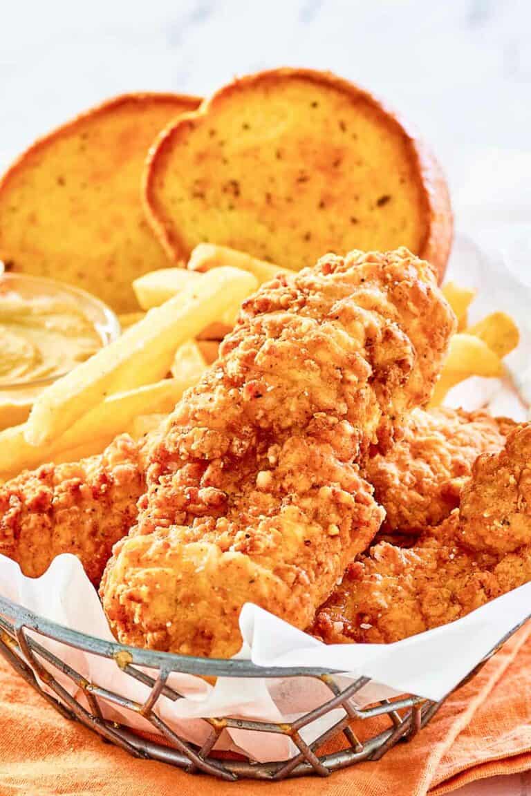 Copycat Whataburger chicken strips, fries, toast, and dipping sauce in a basket.