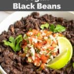 Homemade Chili's black beans in a bowl topped with lime wedges and pico de gallo.